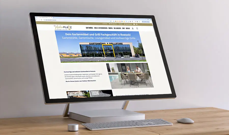 Ein Computermonitor auf einem Holztisch zeigt eine Website für ein Gartenmöbel- und Grillgeschäft in Harburg.
