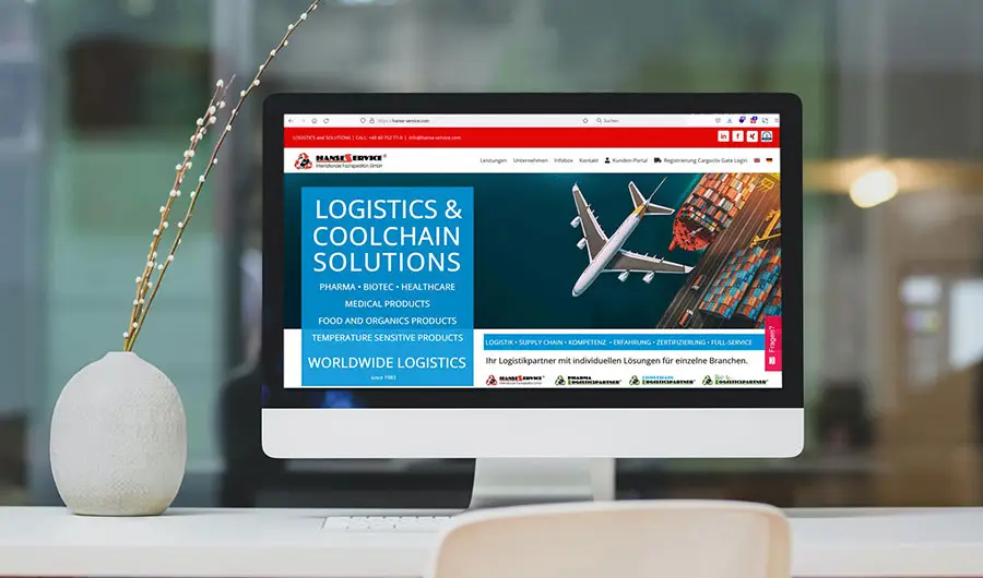 Ein Computermonitor auf einem Schreibtisch zeigt eine Hamburger Website für Logistik- und Kühlkettenlösungen mit Bildern von Flugzeugen und Fracht.
