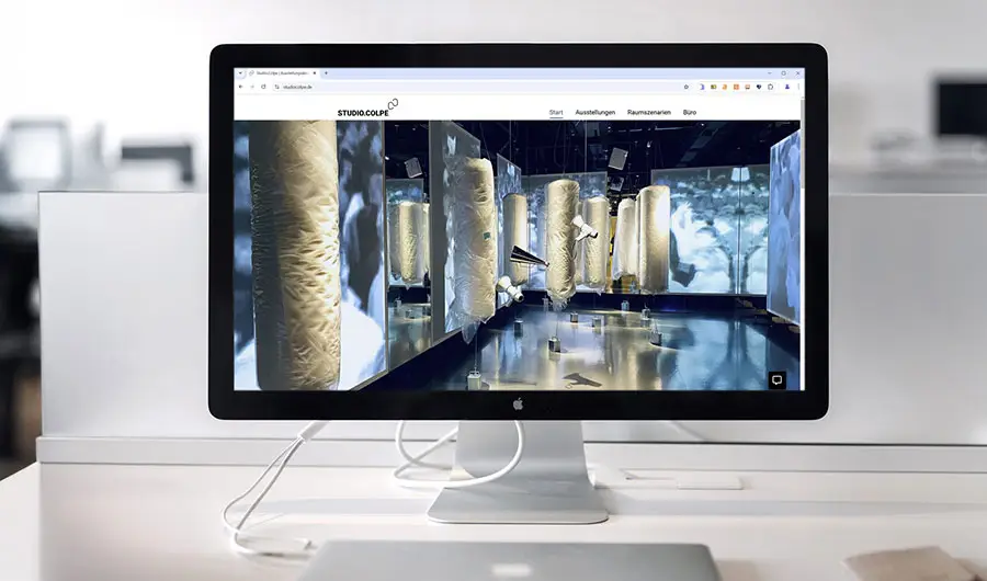 Ein Desktop-Monitor zeigt Webdesign für goldene Skulpturen in einer modernen, minimalistischen Hamburger Büroumgebung.